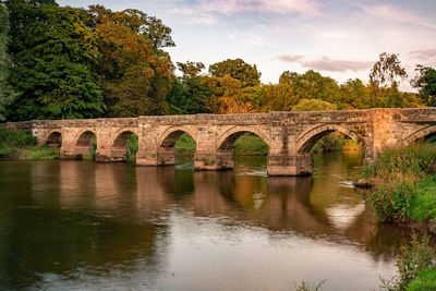 Arch bridge over river against sky