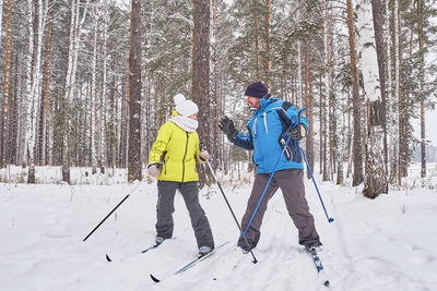 Quarrel of mature couple in winter sportswear cross-country skiing in snowy forest. emotions concept