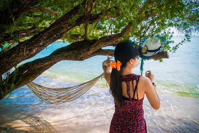 Woman standing by tree against plants