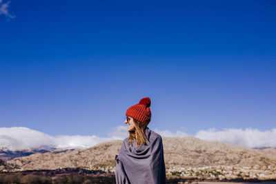 Rear view of person standing against blue sky