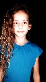 Close-up portrait of smiling girl against black background