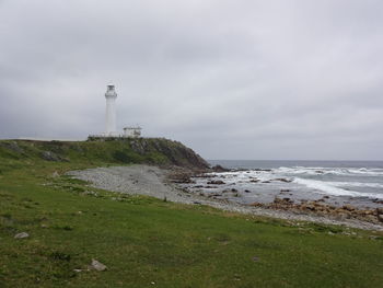 Lighthouse by sea against sky