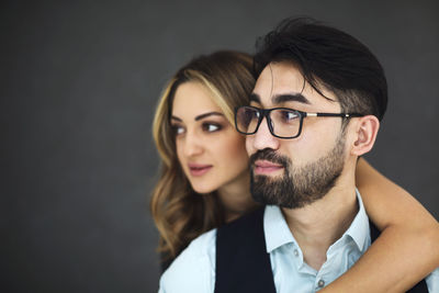 Young couple looking away against black background