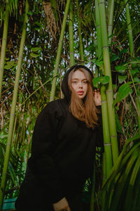 Portrait of young woman standing against plants