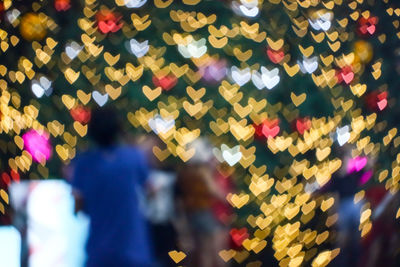 Defocused image of people standing by multi colored lights