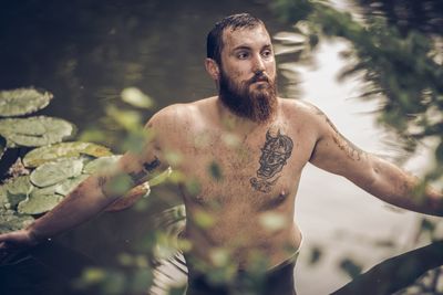 High angle view of shirtless thoughtful man standing in lake