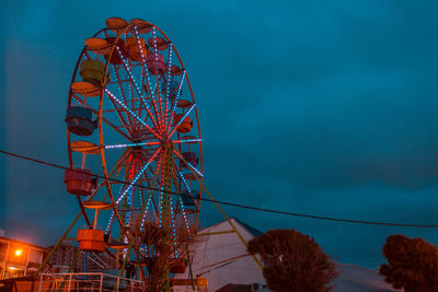 Low angle view of illuminated ferris wheel against blue sky