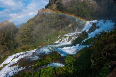 Idyllic view of rainbow over waterfall in forest