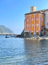 Building by sea against clear blue sky