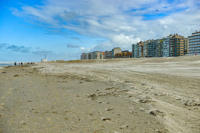 Scenic view of beach by buildings against sky