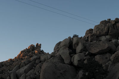 Low angle view of rocks on mountain against clear sky