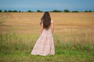 Rear view of young woman standing on field