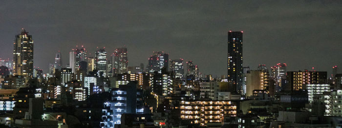 Illuminated cityscape against sky at night