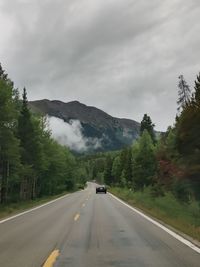 Road amidst trees against sky