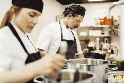 Manlig och kvinnlig kock förbereder mat i restaurangkök