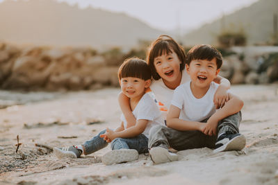 Happy friends sitting on shore at beach