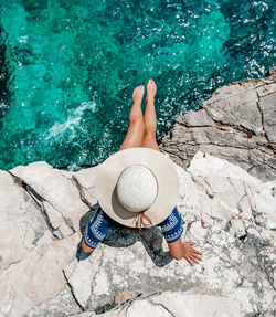 Young woman in summer outfit on cliff above sea.