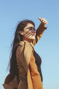 Low angle view of woman standing against clear sky