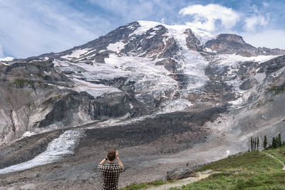 Rear view of man standing against snowcapped mountain 