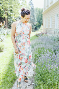 Happy multiracial japanese woman in romantic floral maxi dress in summer park