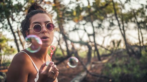 Young woman blowing bubbles at park