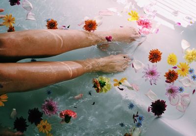 Low section of woman with flowers in water