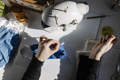 Top view of crop tailor sewing rubber band to fabric mask in workshop