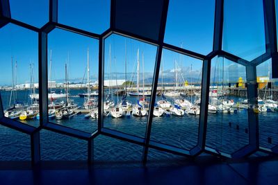 Boats moored at harbor against clear blue sky