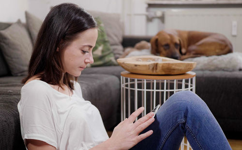 Side view of young woman sitting on sofa at home