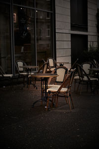 Empty chairs and tables in cafe against buildings in city