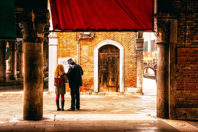 Rear view of people walking on street amidst buildings