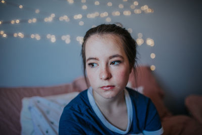 Portrait of young woman sitting on bed at home