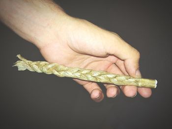 Close-up of cropped hand holding glass over white background