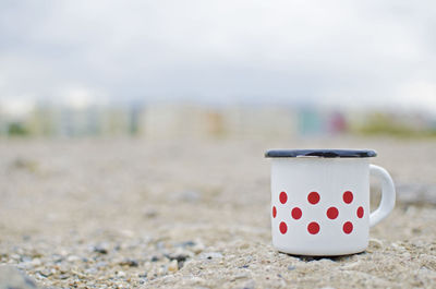 Close-up of mug on beach
