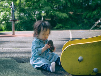 Full length of cute girl holding playing with shoe on playground