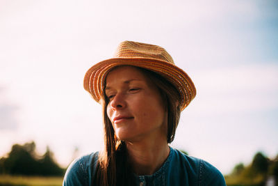Close-up of young woman wearing hat against sky