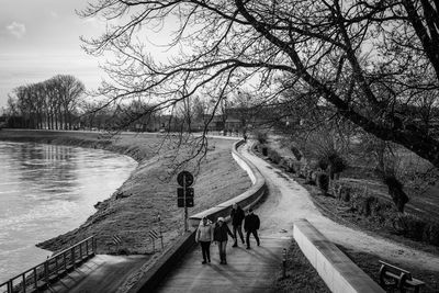 Rear view of people walking on road against sky