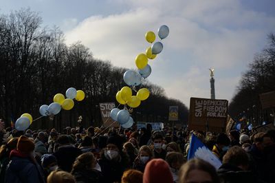 People with balloons against sky