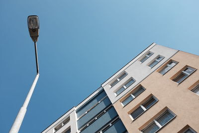 Low angle view of street light by building against clear blue sky