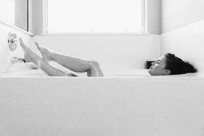 Full length of woman relaxing in bathtub
