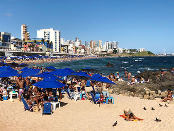 People on beach against clear blue sky