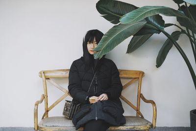 Portrait of young woman standing by plant