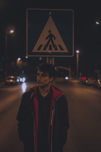 Portrait of man standing on road at night