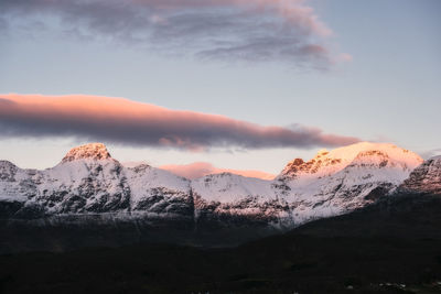 Snowcapped mountains against sky at sunset