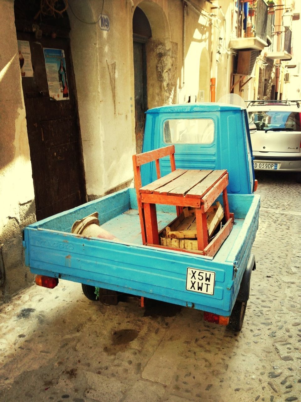 built structure, architecture, building exterior, blue, text, communication, day, empty, absence, no people, outdoors, western script, chair, transportation, street, multi colored, mode of transport, seat, bench, sunlight