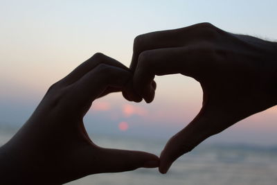 Close-up of heart against sky during sunset at a beach