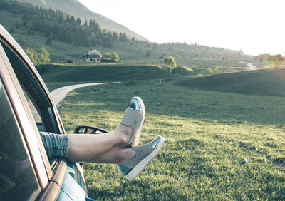 Low section of woman relaxing on landscape against sky