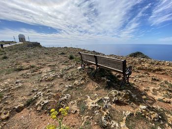 Bench on beach by sea against sky