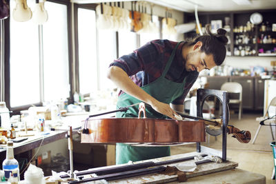 Man cleaning violin on stand while working in workshop