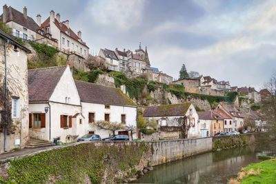 Houses by river in town against sky